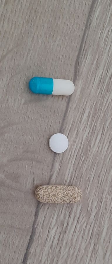 Une gélule et deux comprimés posés sur une table